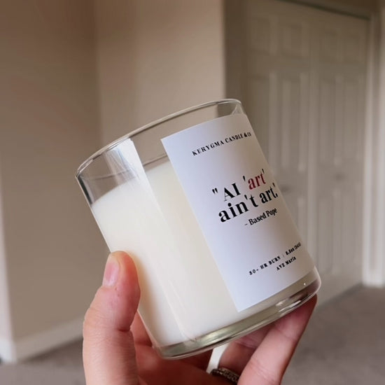 close-up of text label reading "AI Art Isn't Art. - based pope" on a handmade coconut wax Catholic candle.
