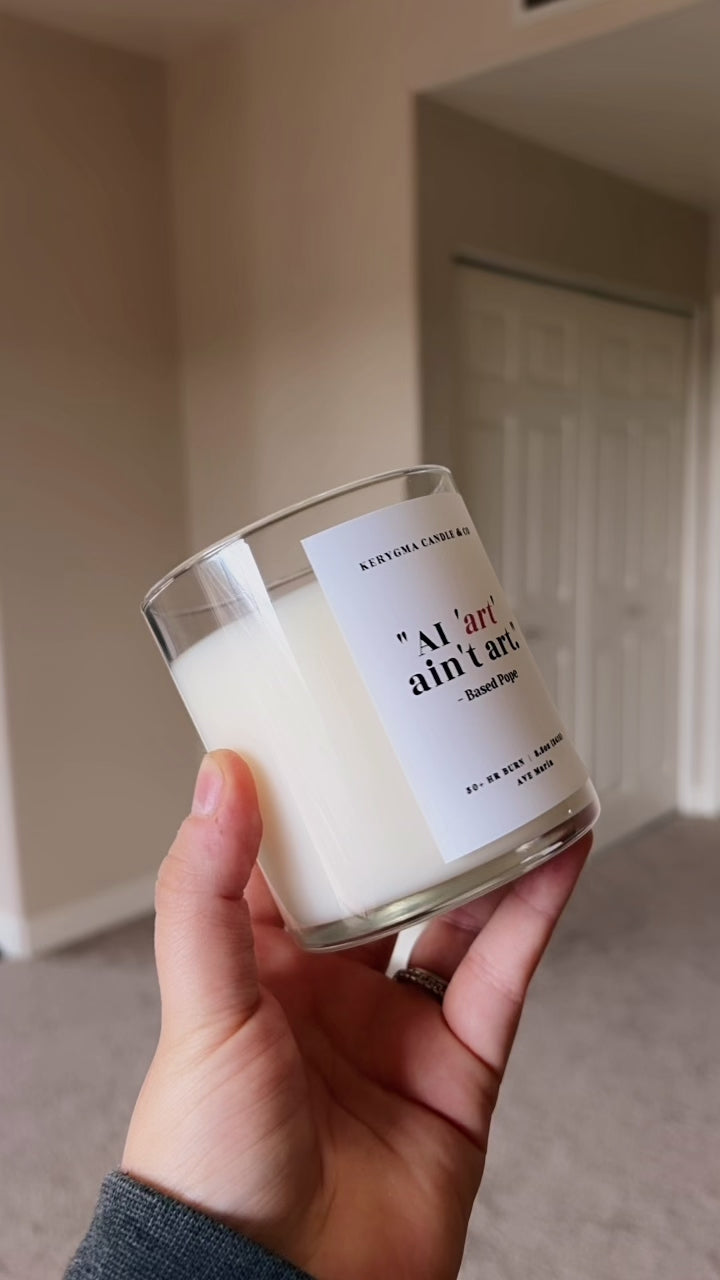 close-up of text label reading "AI Art Isn't Art. - based pope" on a handmade coconut wax Catholic candle.
